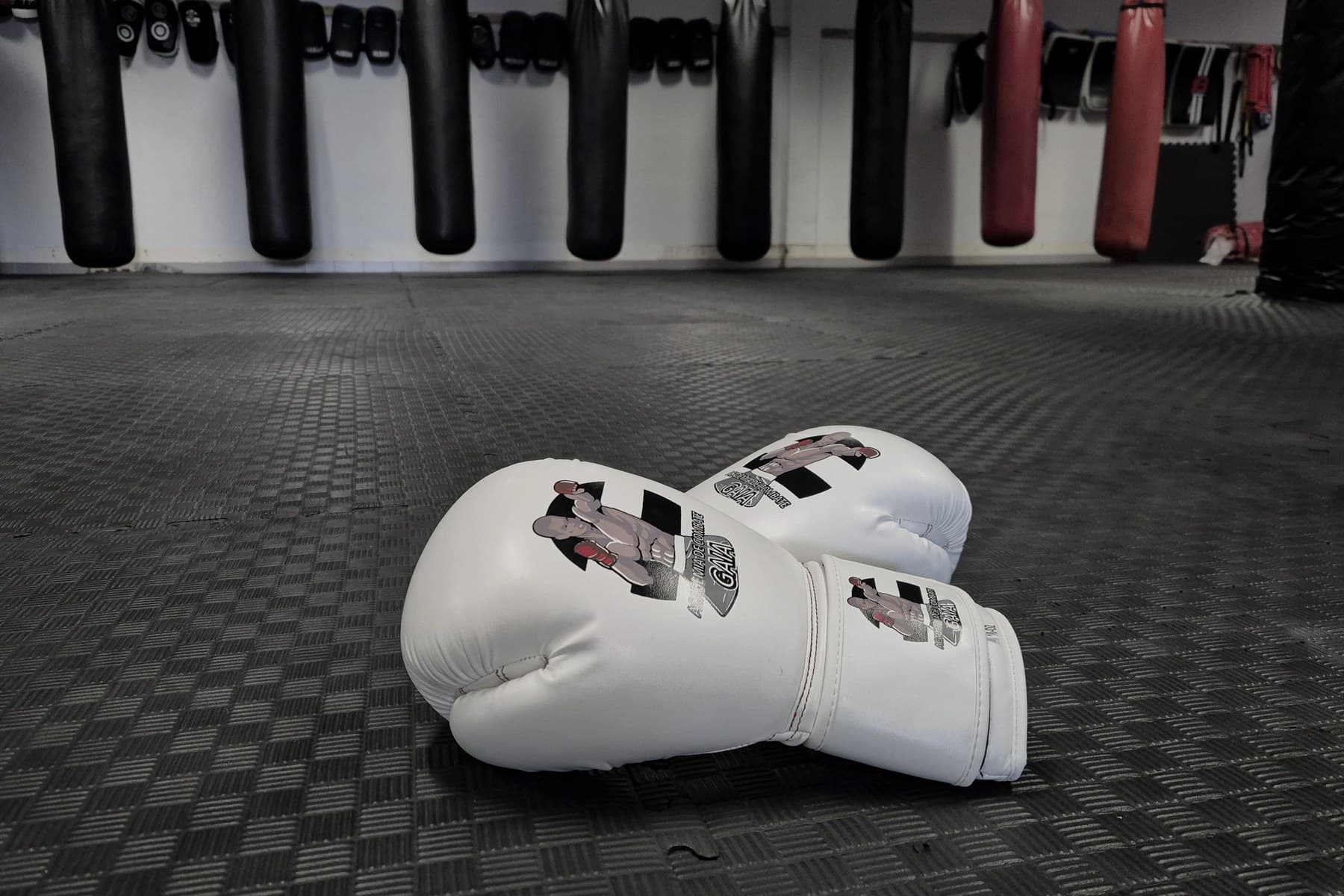 Luvas da Academia Combate de Gaia em frente à parede de sacos de treino
